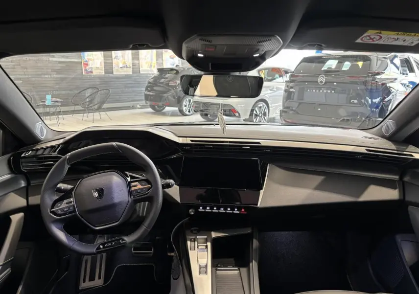 Vue intérieure avant de la Peugeot 308 gris selenium, volant compact GT et écran tactile central noir brillant.