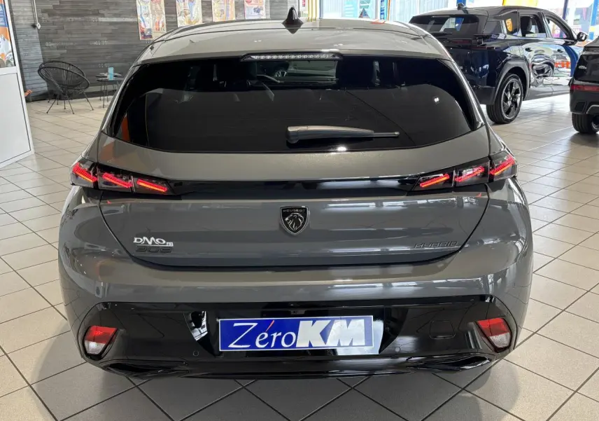 Vue arrière d'une Peugeot 308 hybride gris selenium avec feux arrière LED 3 griffes et bandeau noir brillant en concession.