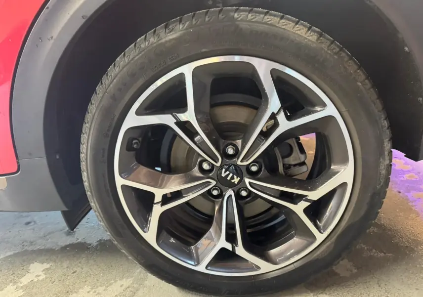 Gros plan sur la roue avant droite du Kia Sportage rouge 2019, mettant en valeur la jante alliage au design moderne.