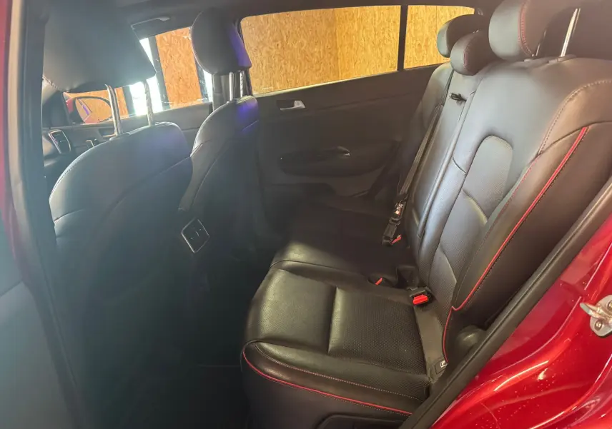 Vue intérieure arrière côté droit du Kia Sportage rouge 2019, sièges cuir noir avec surpiqûres rouges et appuie-têtes réglables.