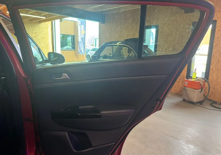 Vue intérieure de la porte arrière gauche rouge du KIA SPORTAGE 1.6 CRDI 136 GT LINE, avec garniture noire et poignée intégrée.