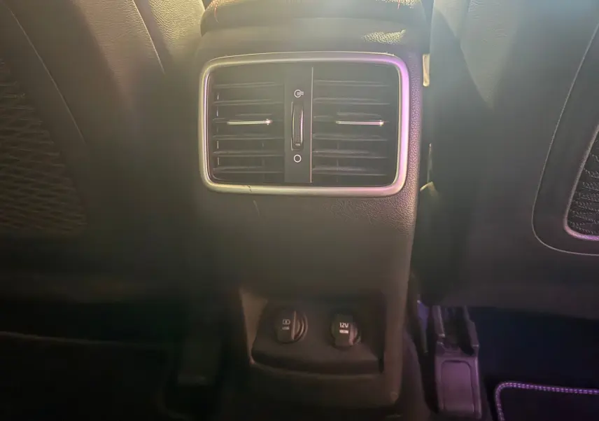 Vue rapprochée des aérateurs arrière et prises 12V du siège arrière d’un KIA Sportage rouge 2019, intérieur noir.
