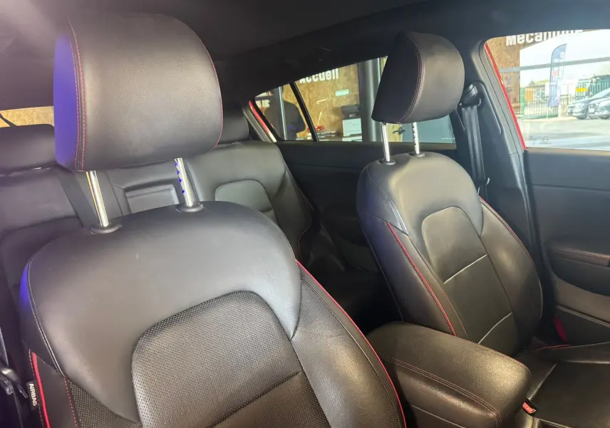 Intérieur du Kia Sportage 2019 en cuir noir avec surpiqûres rouges, vue rapprochée des sièges avant côté droit.