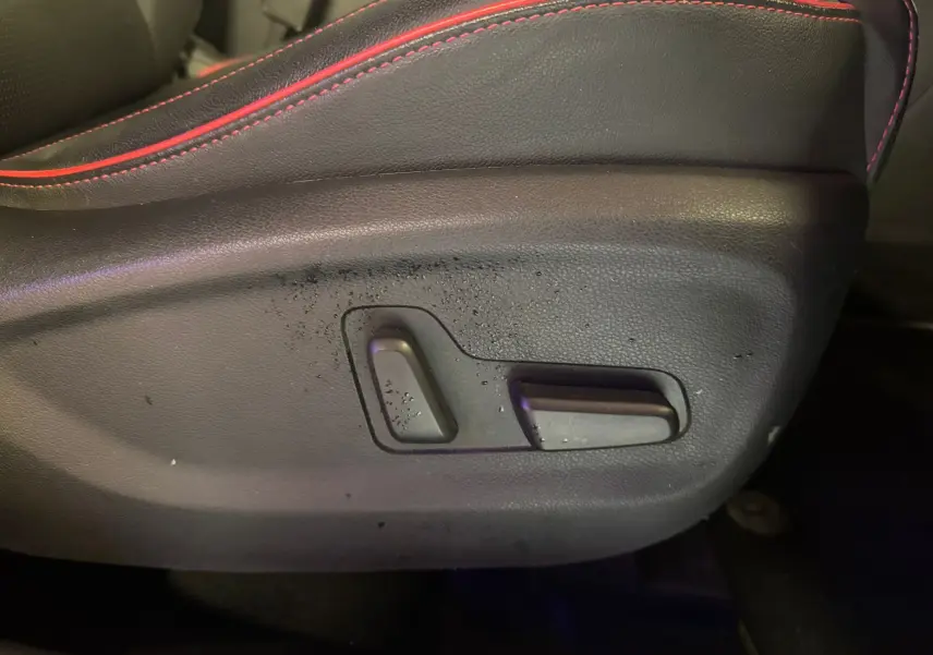 Détail des commandes de réglage électrique du siège avant en cuir noir avec surpiqûres rouges d’un KIA Sportage rouge 2019.