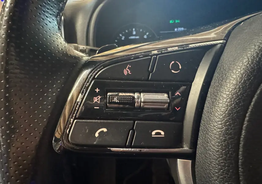 Gros plan sur les commandes multifonctions côté gauche du volant en cuir noir du Kia Sportage rouge, version GT Line 2019.