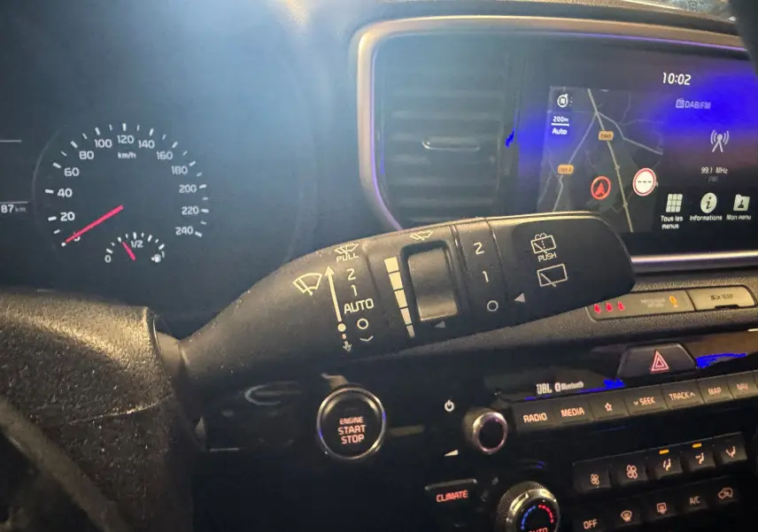 Vue intérieure du tableau de bord du Kia Sportage rouge 2019, mettant en valeur la commande d'essuie-glace et l'écran GPS.