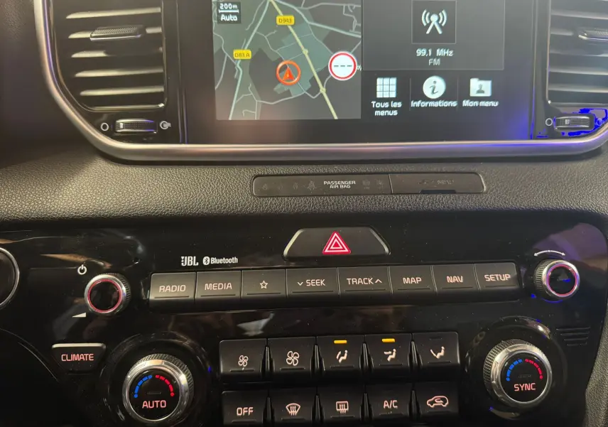 Vue rapprochée de la console centrale du Kia Sportage rouge 2019, avec écran tactile GPS et commandes climatisation.