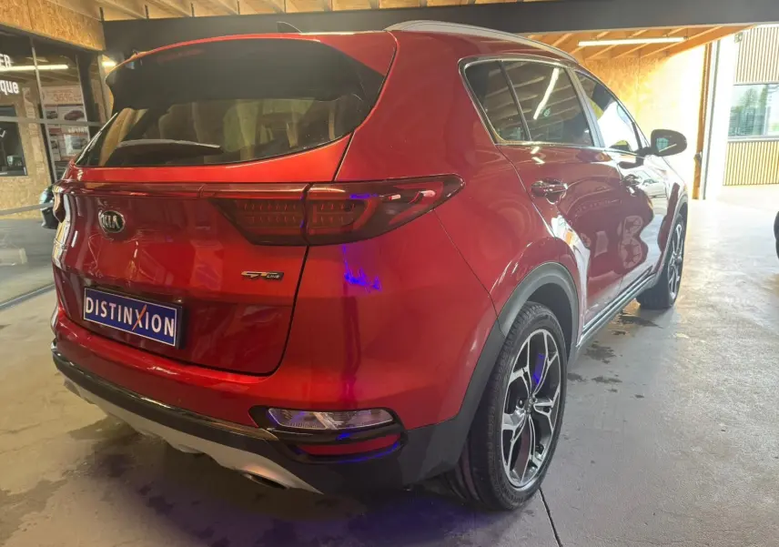 Vue 3/4 arrière droite d'un KIA Sportage rouge 2019 GT Line avec jantes alliage et feux arrière LED.
