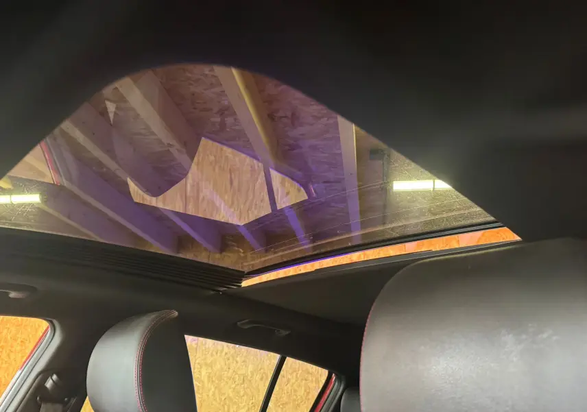 Vue intérieure du toit ouvrant panoramique du Kia Sportage rouge 2019, avec sièges en cuir noir visibles.