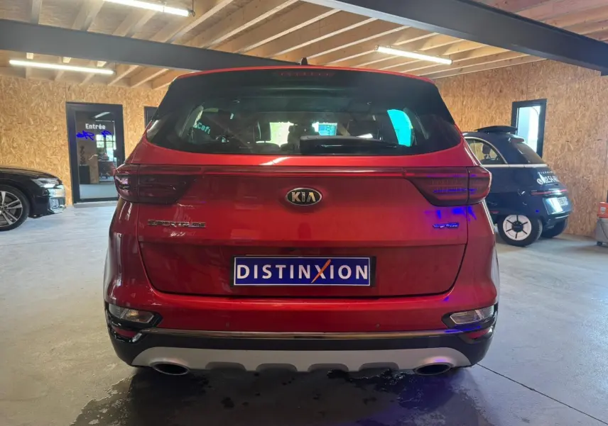 Vue arrière d'un KIA Sportage rouge 2019 en intérieur, avec feux LED et double sortie d'échappement visibles.