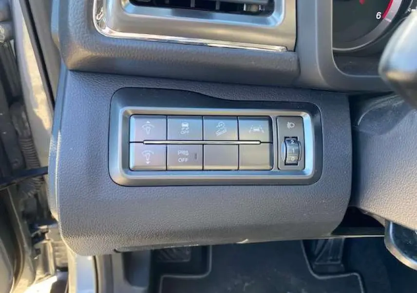 Gros plan sur les commandes d'assistance et réglage des phares du SSANGYONG TIVOLI gris foncé, côté conducteur.