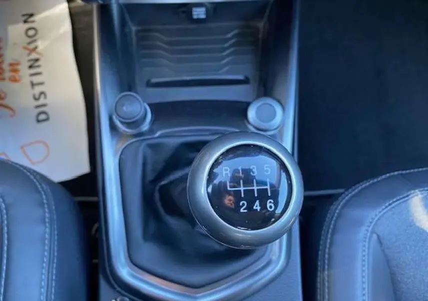 Le levier de vitesses manuel noir du SSANGYONG TIVOLI 160 e-XDi 2WD vu de dessus entre les sièges en cuir gris foncé.
