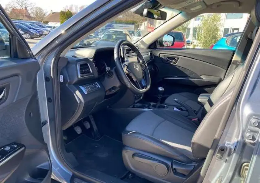Vue intérieure côté conducteur du SsangYong Tivoli gris foncé 2021, volant cuir et tableau de bord moderne.