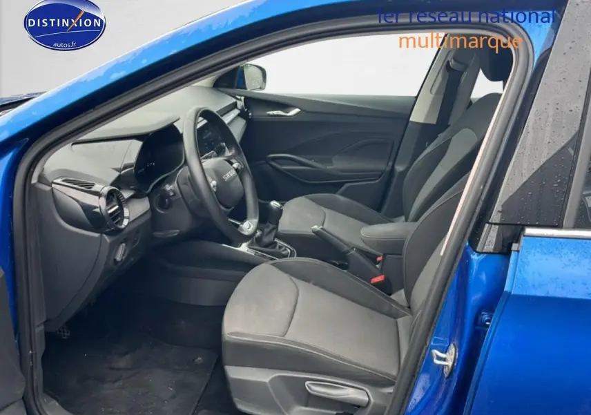 Vue intérieure côté conducteur d'une Skoda Fabia bleu 2025 avec sièges noirs et volant multifonction cuir.
