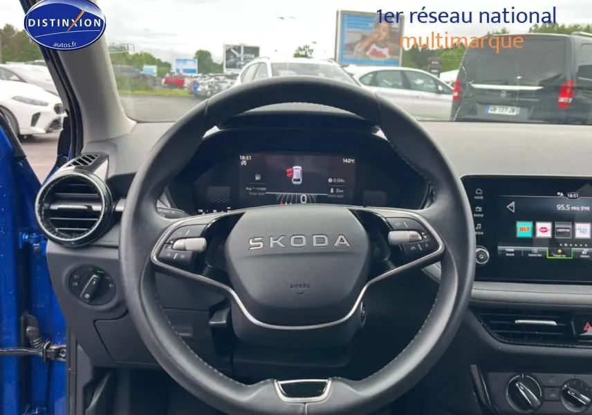 Vue intérieure centrée sur le volant cuir noir de la Skoda Fabia bleu 2025 avec tableau de bord digital et écran tactile.