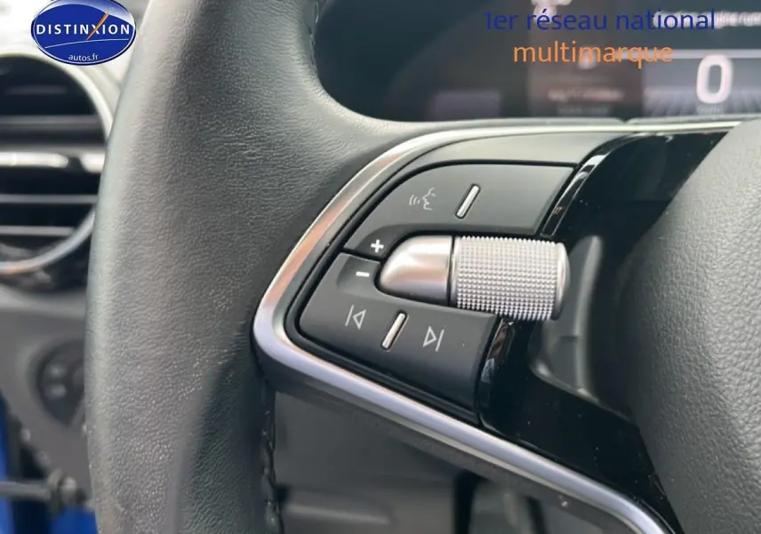 Gros plan sur les commandes du volant cuir noir de la Skoda Fabia bleu, mettant en valeur la molette argentée et les boutons multifonctions.