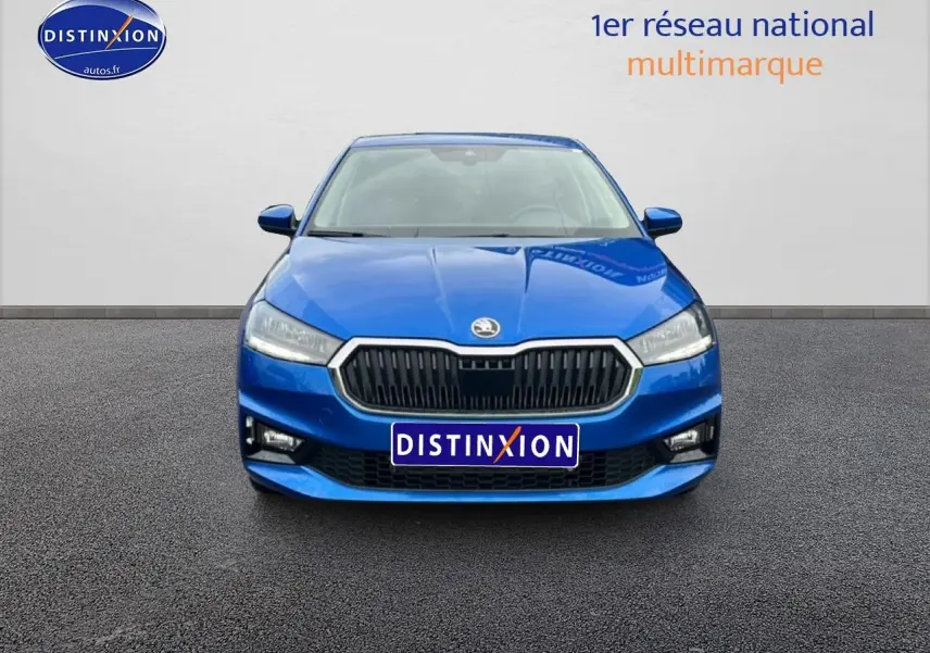 Vue frontale d'une Skoda Fabia bleue 2025 avec calandre noire et phares LED, sur fond neutre gris.