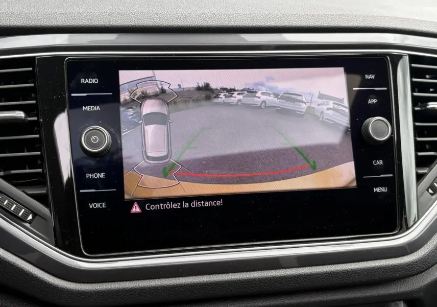 Écran tactile intérieur affichant la caméra de recul du Volkswagen T-Roc 1.5 TSI jaune Curcuma avec guidage de trajectoire.
