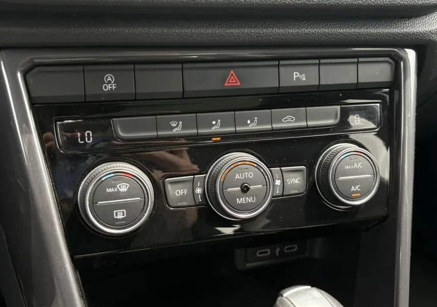 Gros plan sur la console centrale du Volkswagen T-Roc 2021, avec commandes de climatisation et finition noire brillante.