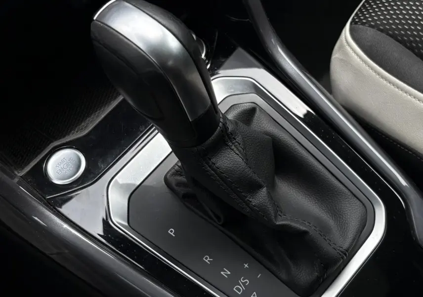 Gros plan sur le levier de vitesses automatique noir et cuir du Volkswagen T-Roc, avec bouton start/stop visible à gauche.