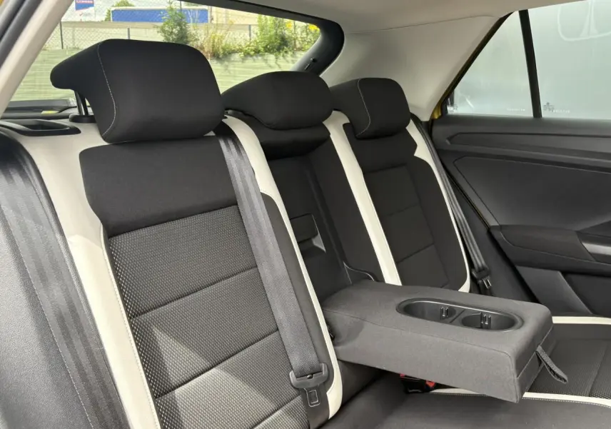 Vue intérieure sur la banquette arrière du Volkswagen T-Roc 1.5 TSI jaune curcuma, avec accoudoir central déplié.
