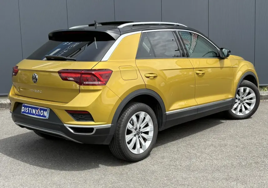 Vue 3/4 arrière droite d'un Volkswagen T-Roc jaune curcuma avec toit noir et jantes alliage 17 pouces.
