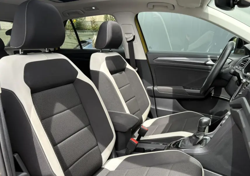 Vue intérieure côté droit du Volkswagen T-Roc 1.5 TSI 150 DSG7 Carat, sièges tissu noir et beige avec volant multifonction.