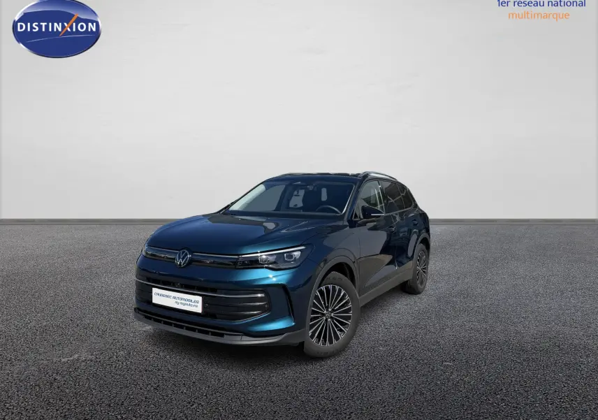 Volkswagen Tiguan 2025 bleu en 3/4 avant droit, avec jantes alliage 18 pouces, devant concession Caudebec Automobiles.