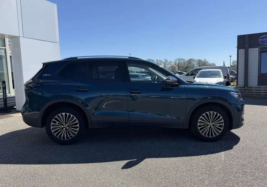 Vue latérale droite d'un Volkswagen Tiguan bleu 2025 avec jantes alliage 18 pouces et vitres teintées.