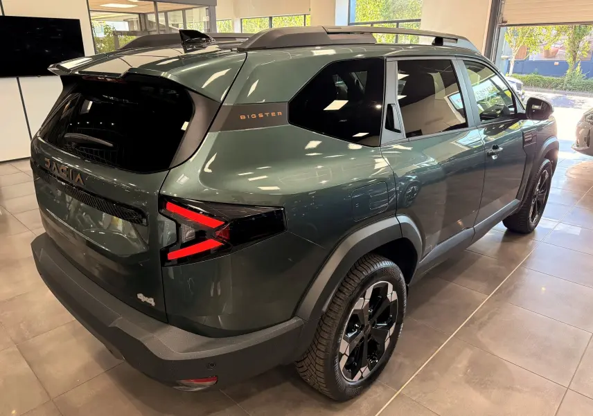 Vue 3/4 arrière droite du Dacia Bigster Hybrid-G 150 4x4 en Vert Cèdre, avec feux arrière en forme de flèche et jantes bicolores.