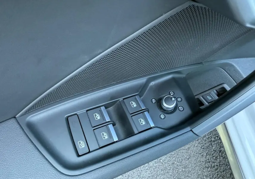 Gros plan sur les commandes des vitres et rétroviseurs côté conducteur de l'Audi A3 Sportback blanc Glacier 2025.