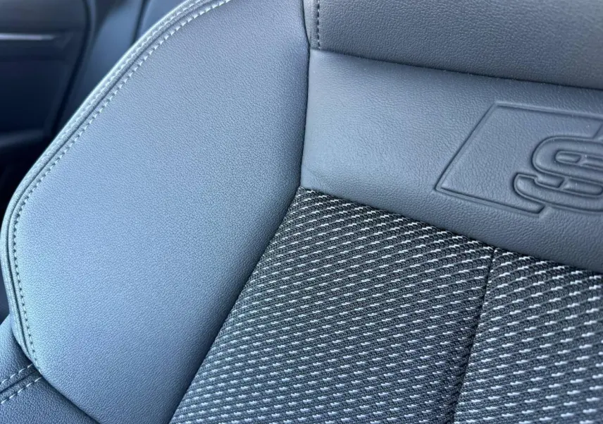 Gros plan sur le siège avant en tissu noir et simili avec logo S line embossé, intérieur Audi A3 Sportback 2025.