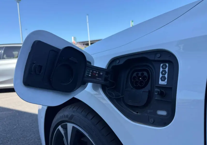Prise de recharge ouverte côté gauche arrière d’Audi A3 Sportback blanc Glacier métallisé, jante alu visible.