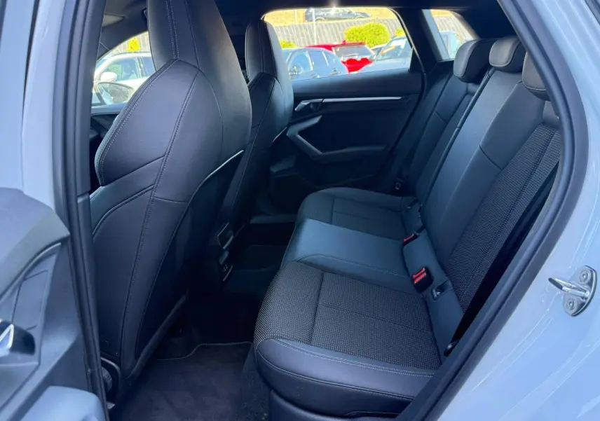 Vue intérieure côté droit sur la banquette arrière noire en tissu et simili de l’Audi A3 Sportback Blanc Glacier.