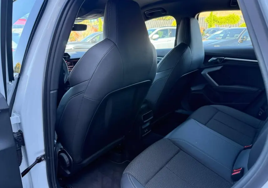 Vue intérieure arrière côté gauche d’une Audi A3 Sportback blanche avec sièges sport noirs et finitions modernes.