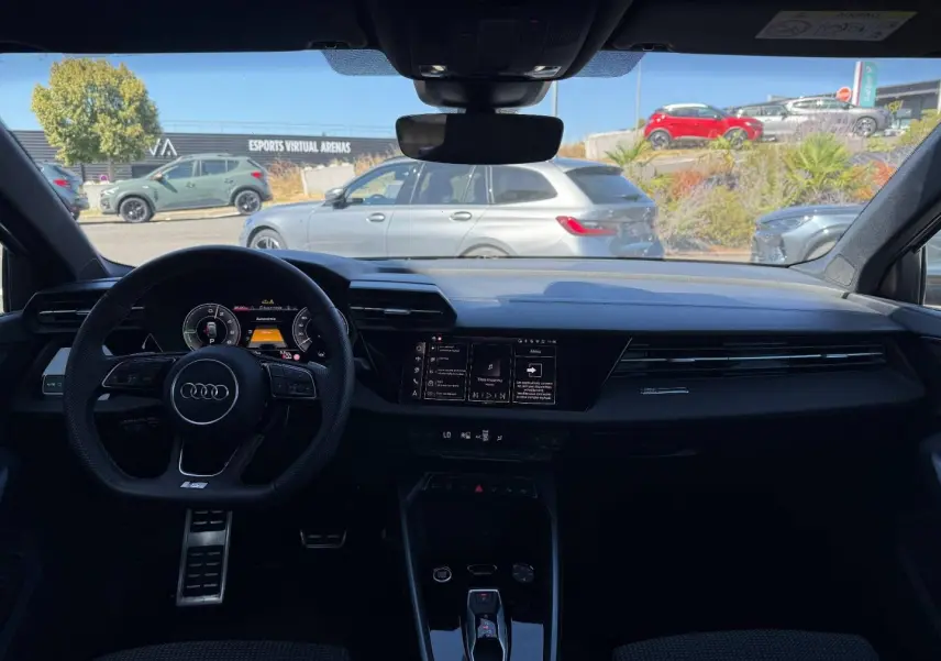 Vue intérieure de l'Audi A3 Sportback 2025, tableau de bord noir avec volant sport et écran multifonction.