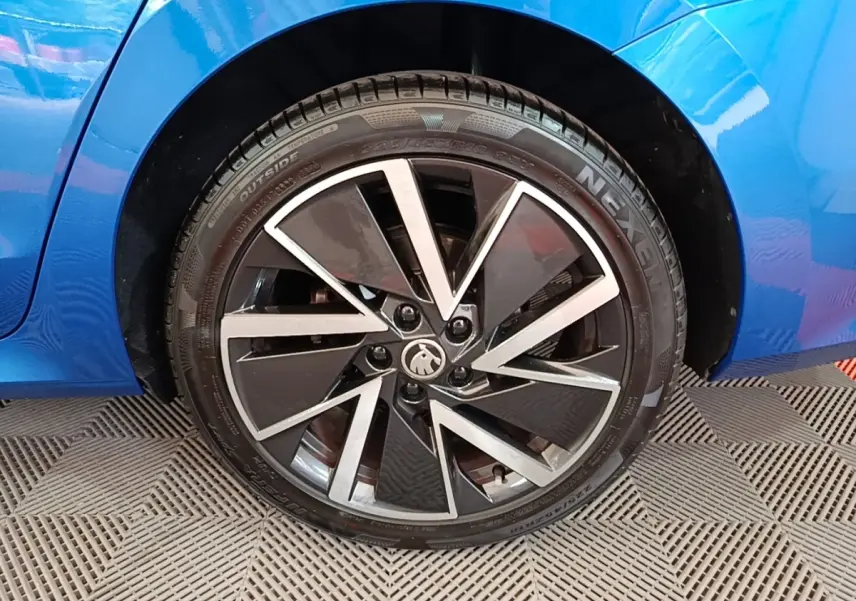 Gros plan sur la roue arrière droite d’une Skoda Octavia bleue 2022 avec jante alliage noire et argentée au design moderne.