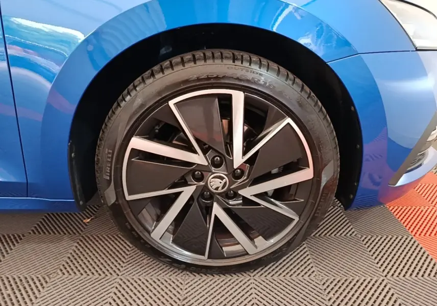 Gros plan sur la roue avant droite d'une Skoda Octavia bleu électrique avec jante alliage noire et argentée.