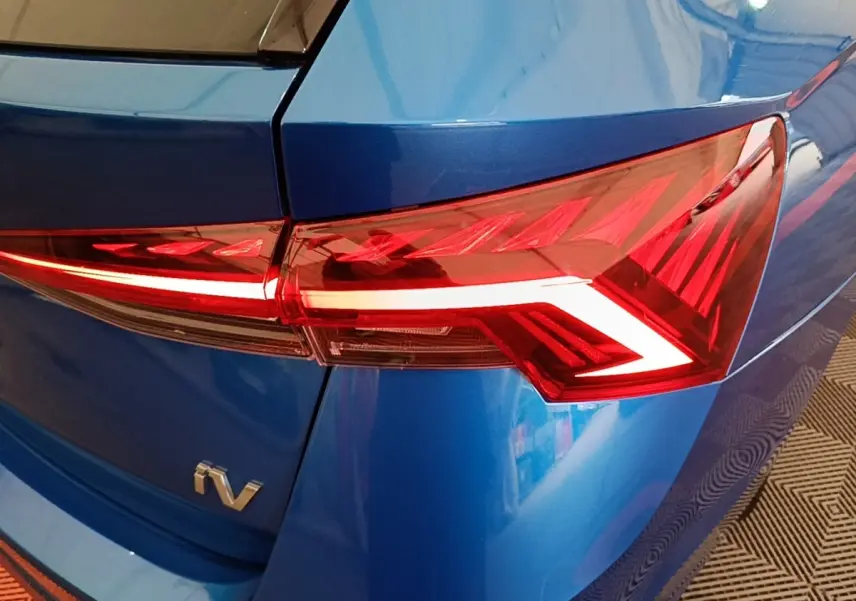Gros plan sur le feu arrière droit rouge d’une Skoda Octavia hybride rechargeable bleue, avec logo iV visible.