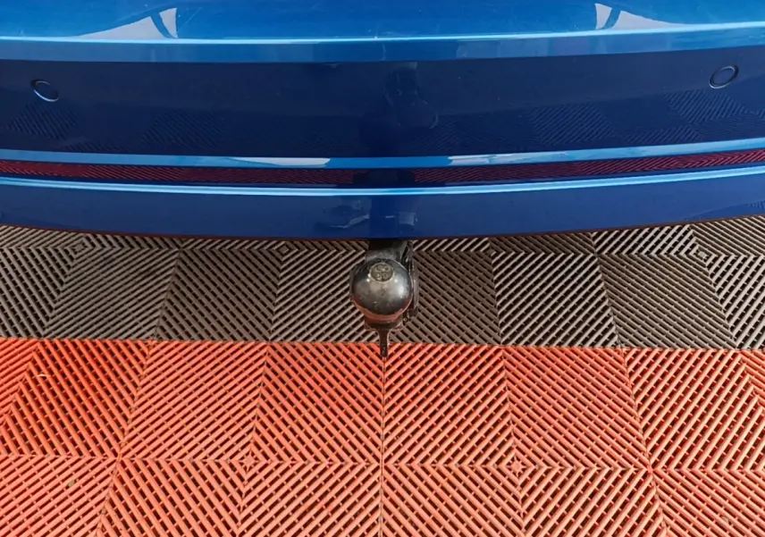 Gros plan sur l'attelage arrière d'une Skoda Octavia bleu, avec pare-chocs et capteurs de stationnement visibles.