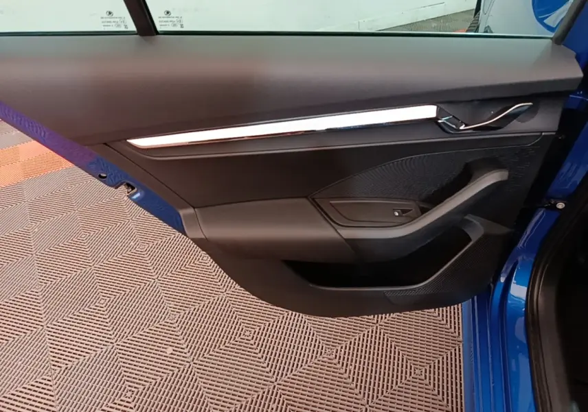 Vue rapprochée de la porte avant gauche d'une Skoda Octavia bleu 2022, avec garniture noire et poignée chromée.