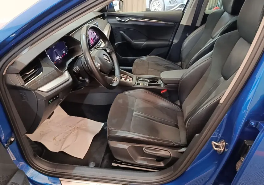 Vue intérieure côté conducteur de la Skoda Octavia bleue 2022, avec sièges noirs et tableau de bord numérique.