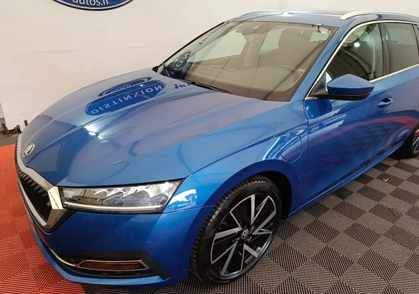 Vue 3/4 avant droite d'une Skoda Octavia bleu électrique avec jantes alliage noires et prises de recharge latérales visibles.