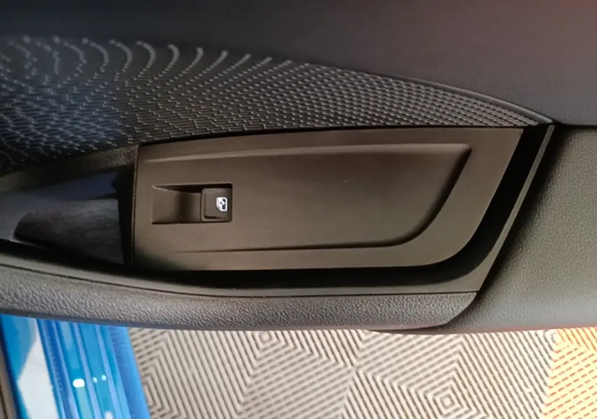 Détail de la commande de lève-vitre sur la porte côté conducteur d’une Skoda Octavia bleu 2022.