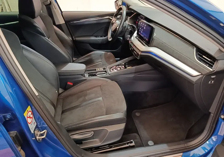 Vue intérieure côté conducteur d'une Skoda Octavia bleu 2022, avec sièges en cuir noir et tableau de bord digital.