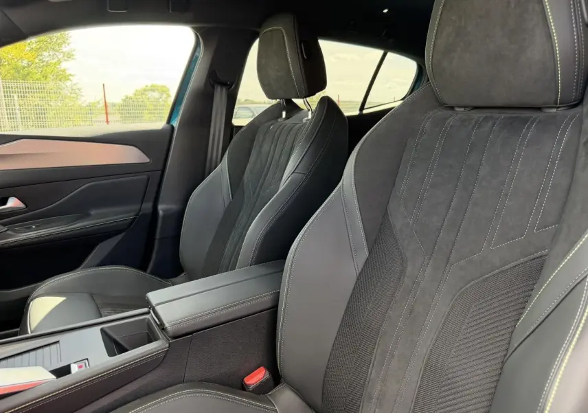Vue intérieure côté droit des sièges avant en tri-matières noires avec surpiqûres contrastantes sur Peugeot 408 Hybrid 2025.