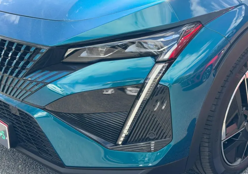 Gros plan sur l'avant droit bleu Obsession du Peugeot 408 Hybrid avec feux LED et jante alu noire.