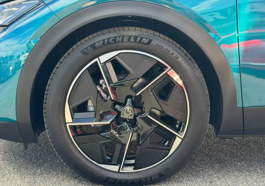 Gros plan sur la roue avant gauche avec jante alu noire et argentée du Peugeot 408 Hybrid Bleu Obsession.
