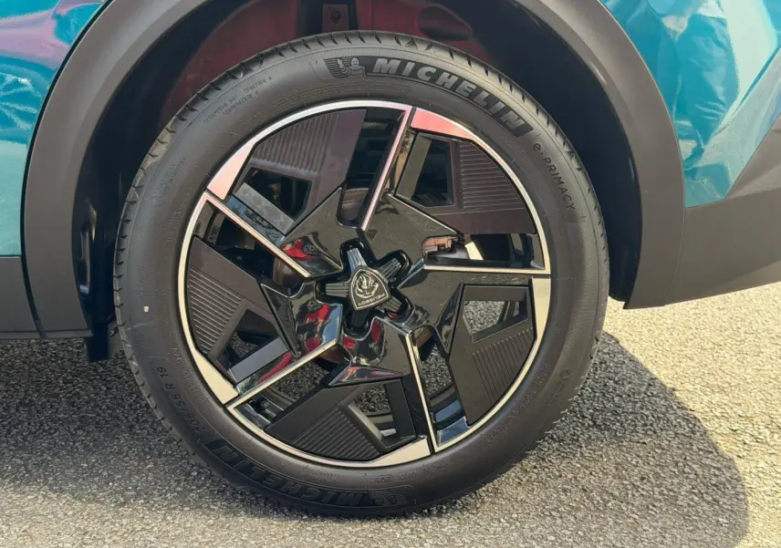 Gros plan sur la roue avant gauche avec jante alu noire et chromée du Peugeot 408 Bleu Obsession.