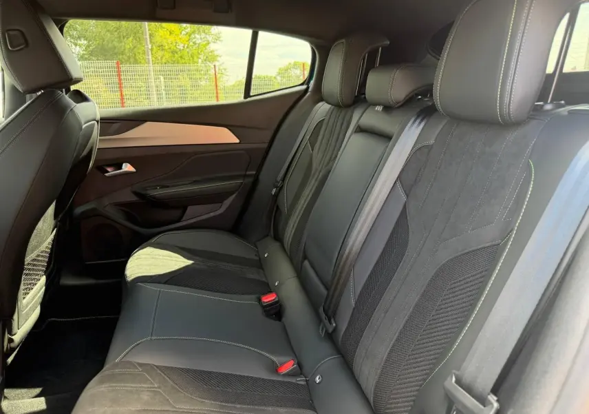 Vue intérieure côté droit des sièges arrière en cuir et tissu noir avec surpiqûres contrastantes du Peugeot 408 Hybrid 2025.